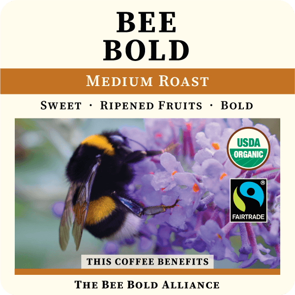 Medium roast coffee beans from Thanksgiving Coffee Company's Bee Bold line, showcasing whole, aromatic beans in a natural setting.