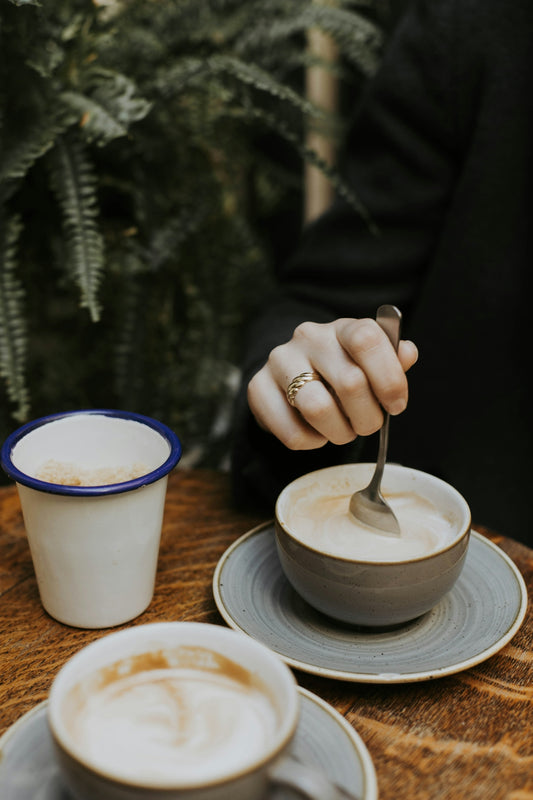 a person holding a spoon in a cup of coffee