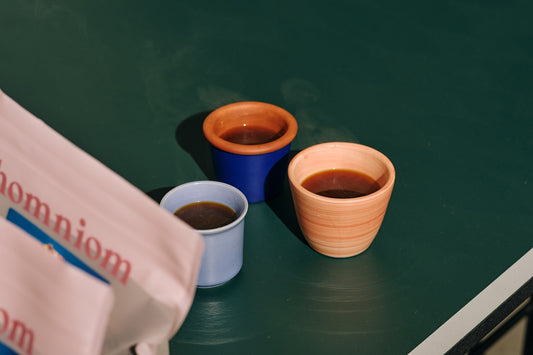 Two cups of coffee sitting on top of a tennis court