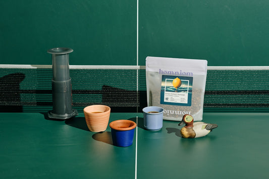 A table topped with a bag of coffee next to a cup