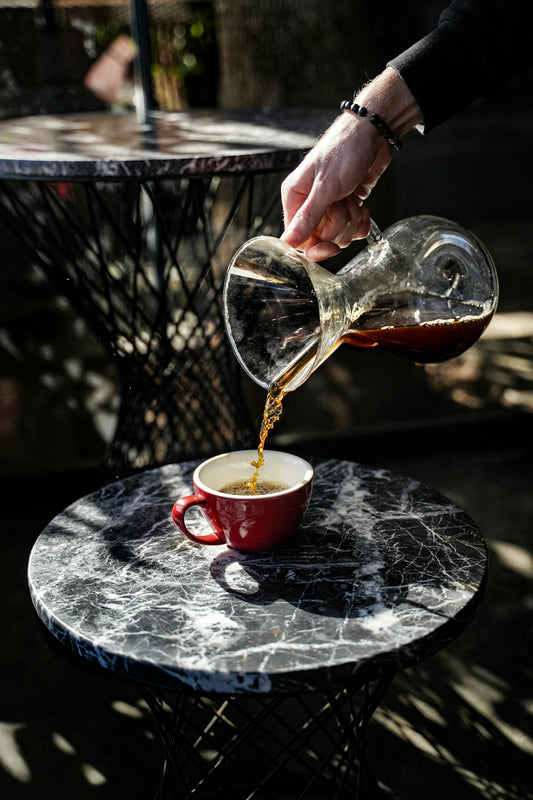 Coffee is being poured into a red cup.