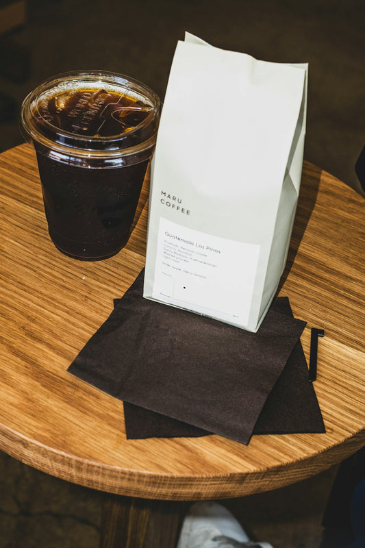 Iced coffee and a bag of beans on a wooden table