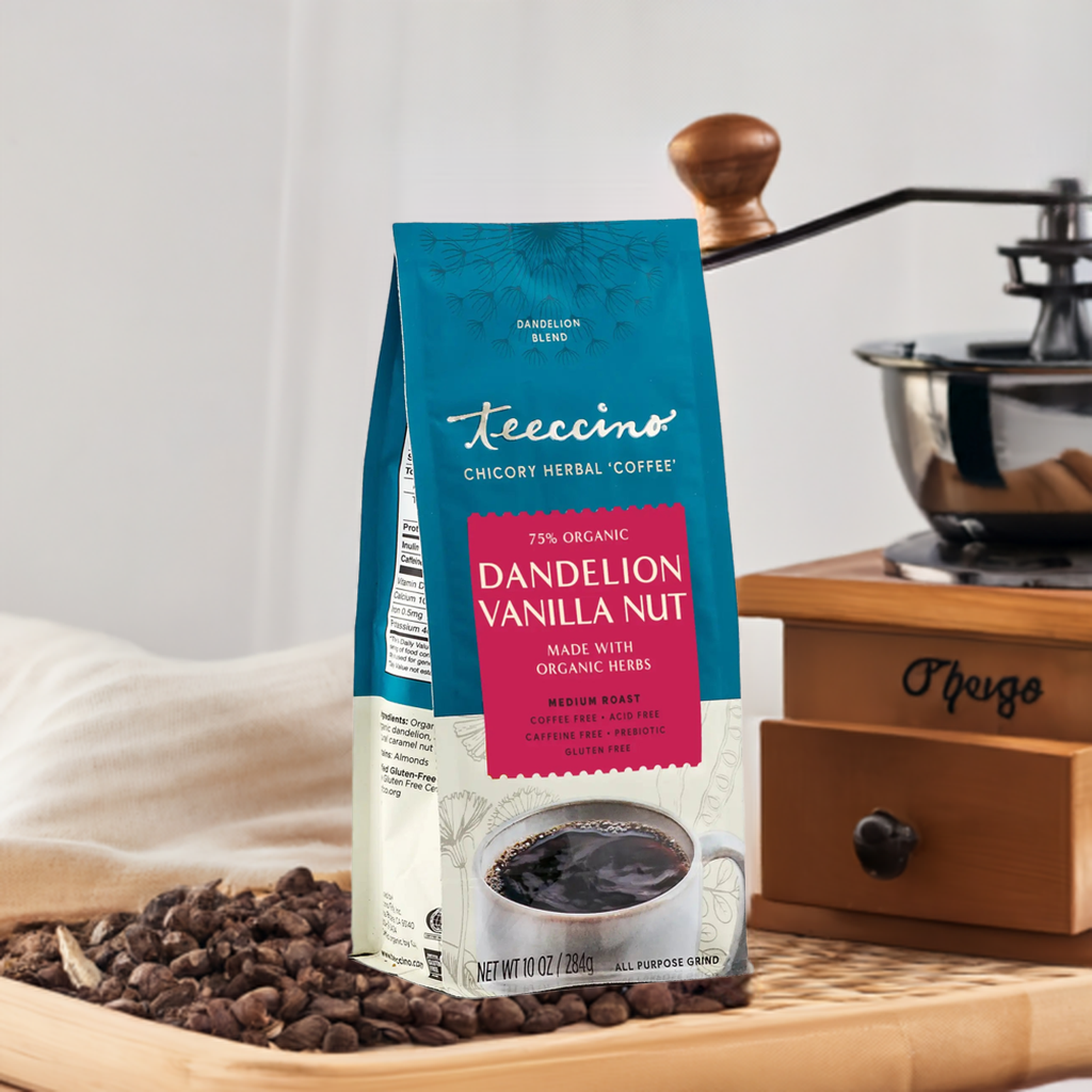 Dandelion Vanilla Nut herbal coffee by Teeccino in a glass mug with vanilla beans and dried herbs on a wooden table.