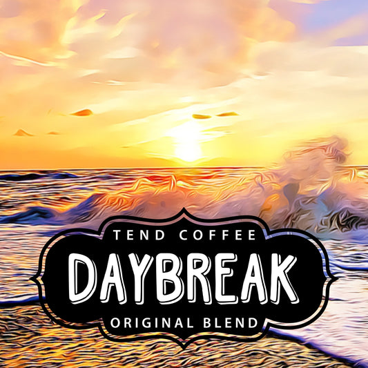 A cup of Daybreak Blend coffee from Tend Coffee showing a steaming brewed coffee in a white mug on a wooden table.