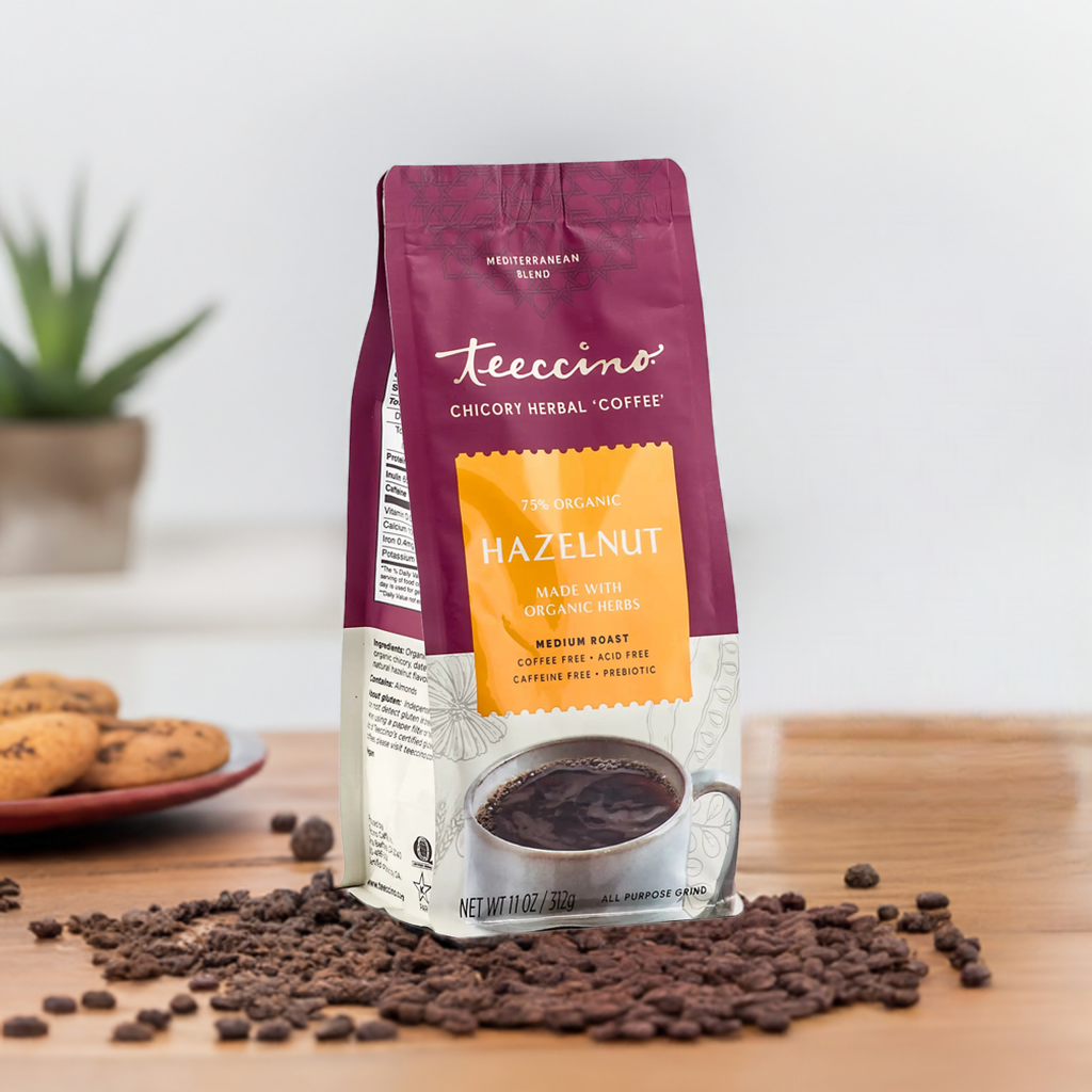 Brewed Hazelnut Chicory Herbal Coffee by Teeccino in a mug with coffee beans and hazelnuts on a wooden table.