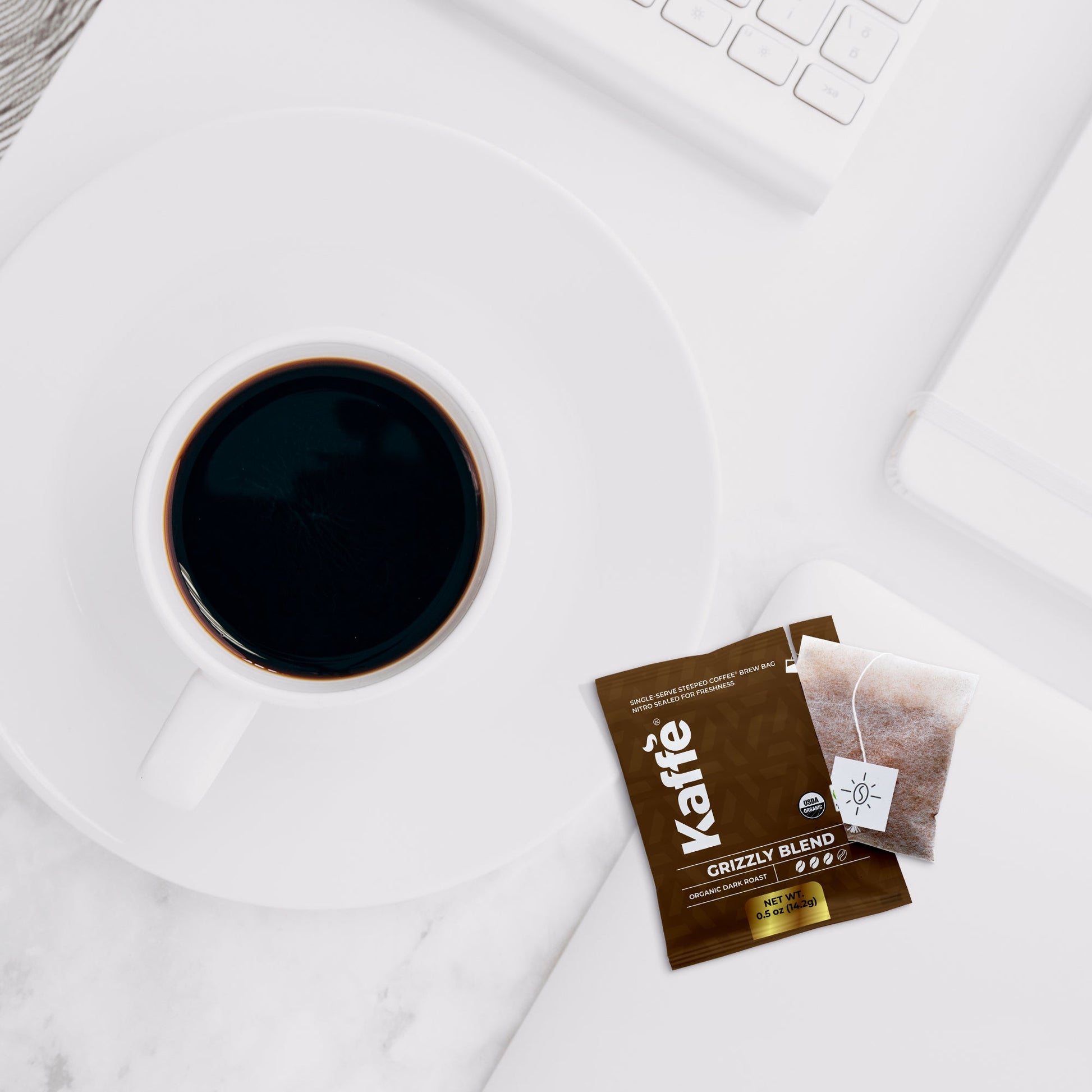 Kaffe Products Grizzly Blend dark roast coffee steeped bags, 5-pack, showing individual steeped coffee bags with rich dark coffee grounds inside.