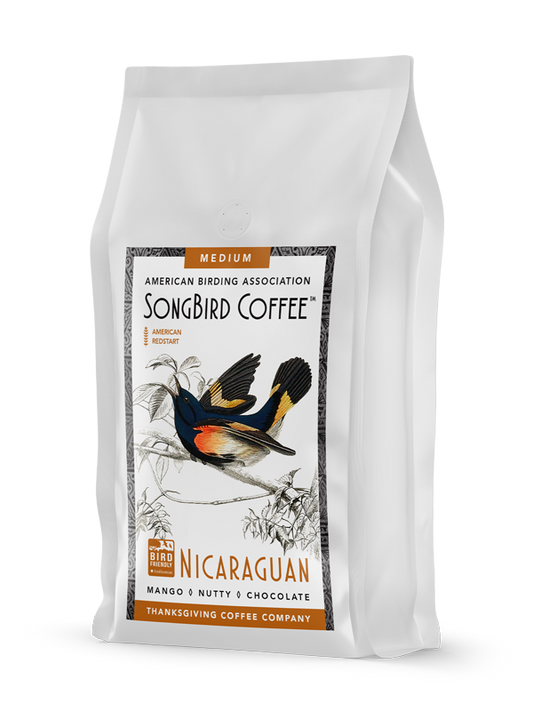 Medium roast SongBird Nicaraguan coffee bag by Thanksgiving Coffee Company, featuring vibrant packaging and fresh coffee beans.