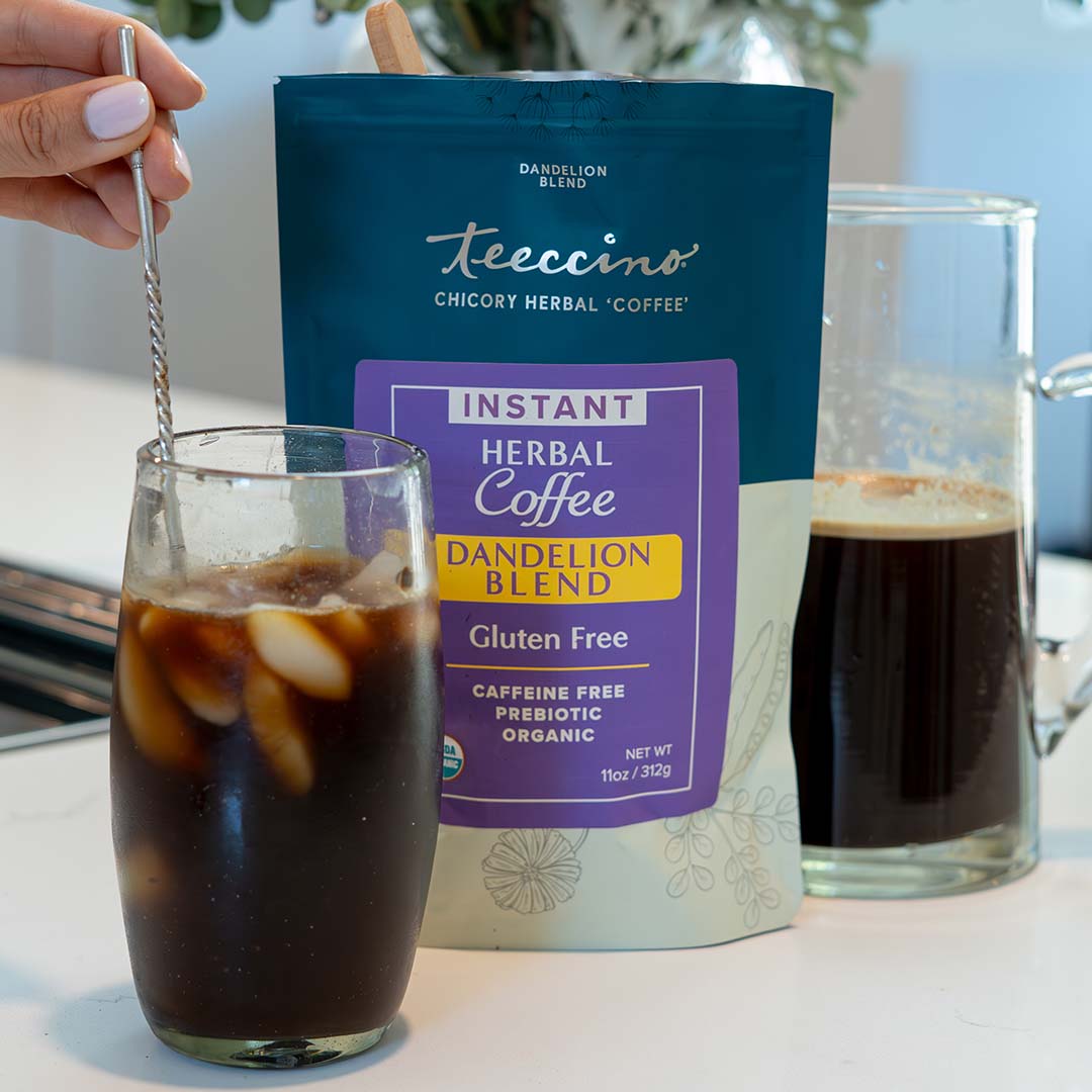 Cup of Teeccino instant Dandelion Herbal Coffee with a steaming mug and herbal blend ingredients on a wooden table.