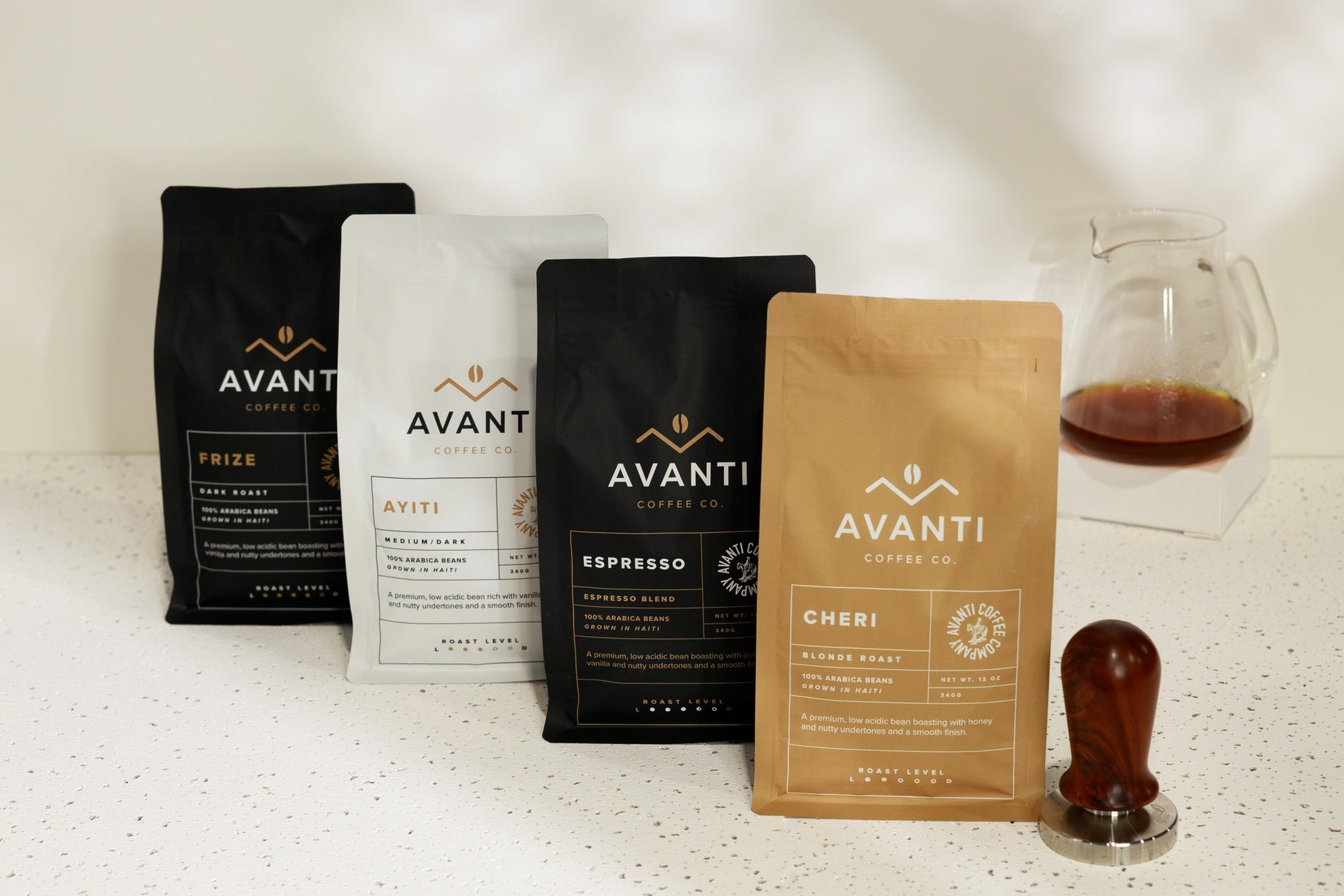 Assorted Avanti Coffee Company coffee beans and accessories in the Ultimate Coffee Lover Gift Set on a wooden table.