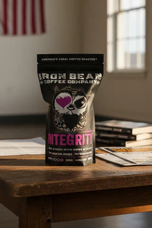 Dark roast coffee from Iron Bean Coffee Company, Integrity™, in a bag with rich, bold roasted beans visible.