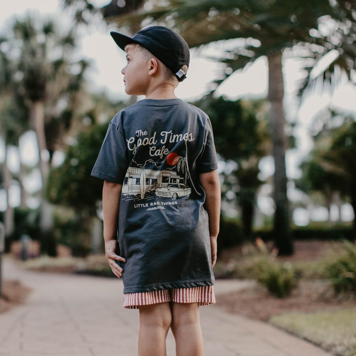 Baby boy wearing THE GOOD TIMES CAFE TEE in coal color from LITTLE RAD THINGS, featuring a casual toddler top with playful design.